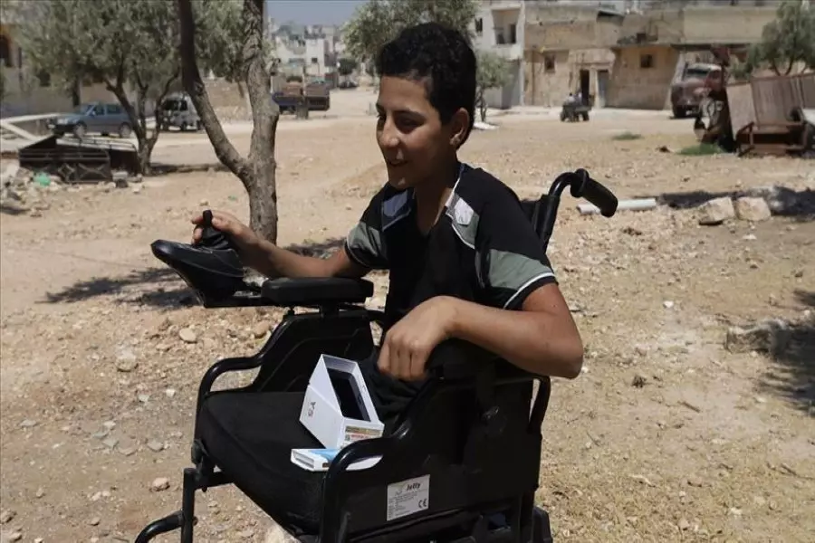 بعدما فقد قدميه بسبب قصف قوات الأسد ... الإغاثة التركية تقدم كرسي متحرك لطفل سوري