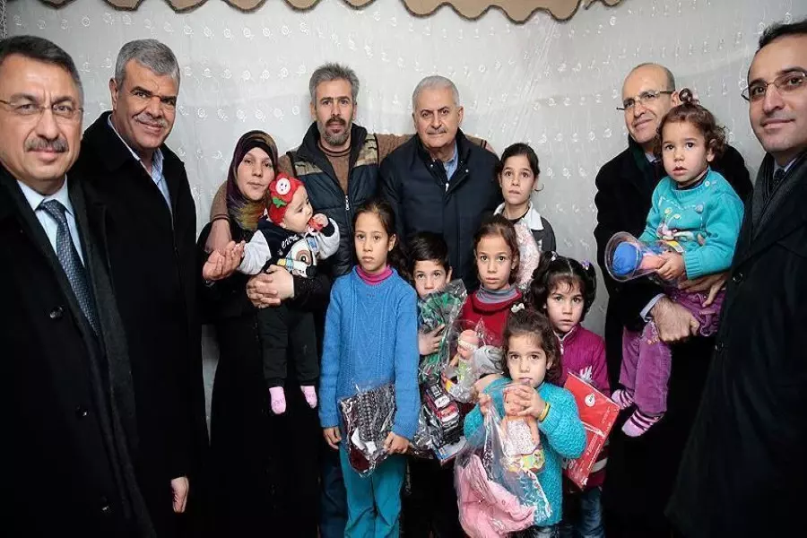 رئيس الوزراء التركي يستقبل عائلة سورية ويلاطف صغيرها