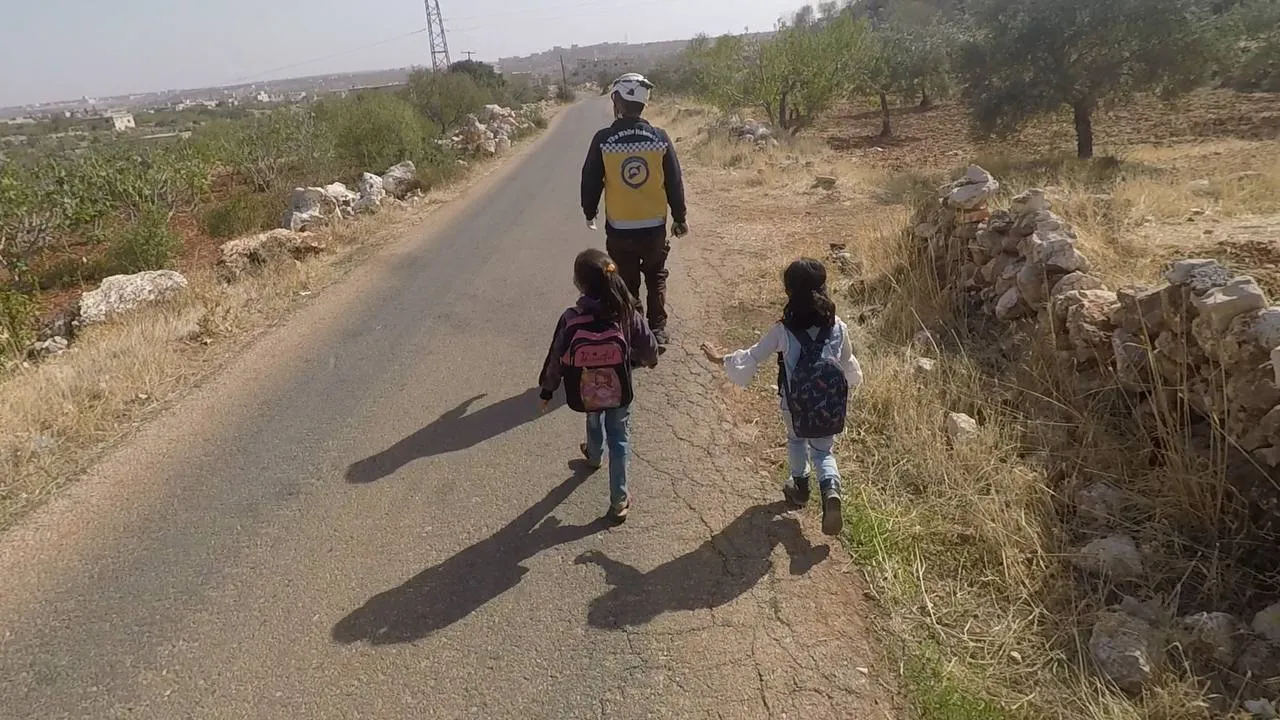 طفلين مع متطوع من الدفاع المدني في الشمال السوري