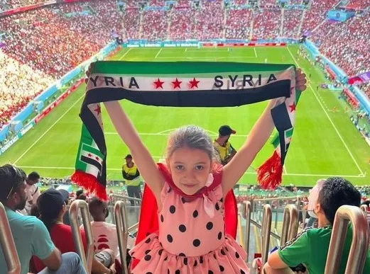 طفلة تحمل علم الثورة في أحد ملاعب كأس العالم