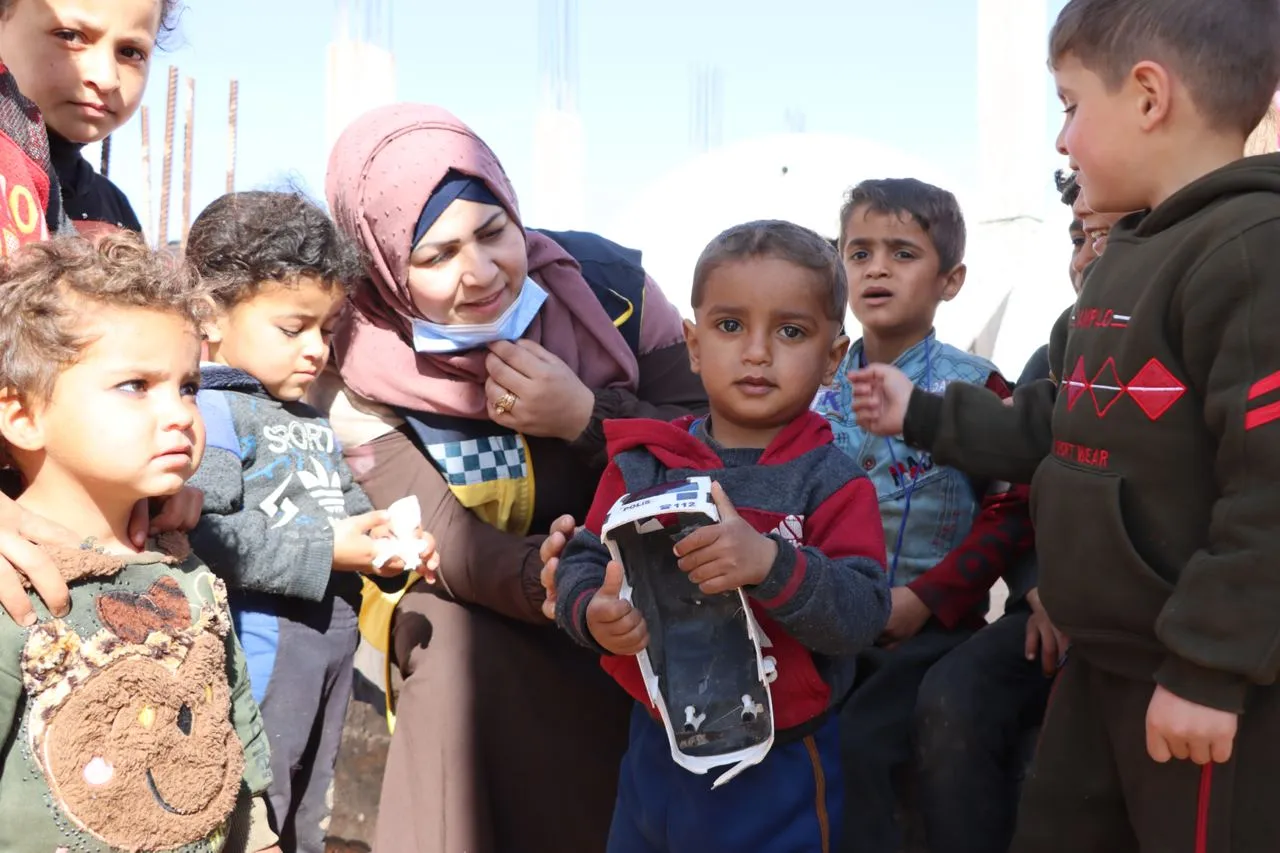 متطوعة من الدفاع المدني مع أطفال في أحد مخيمات الإيواء في الشمال السوري