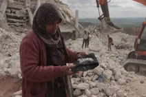 سيدة تقف على أنقاض منزلها المدمر بريف إدلب بفعل الزلزال