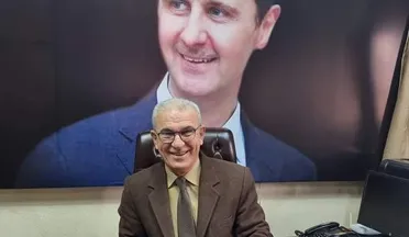 القاضي فؤاد سلوم قبل سقوط نظام الأسد وخلفه صورة كبيرة لبشار الأسد