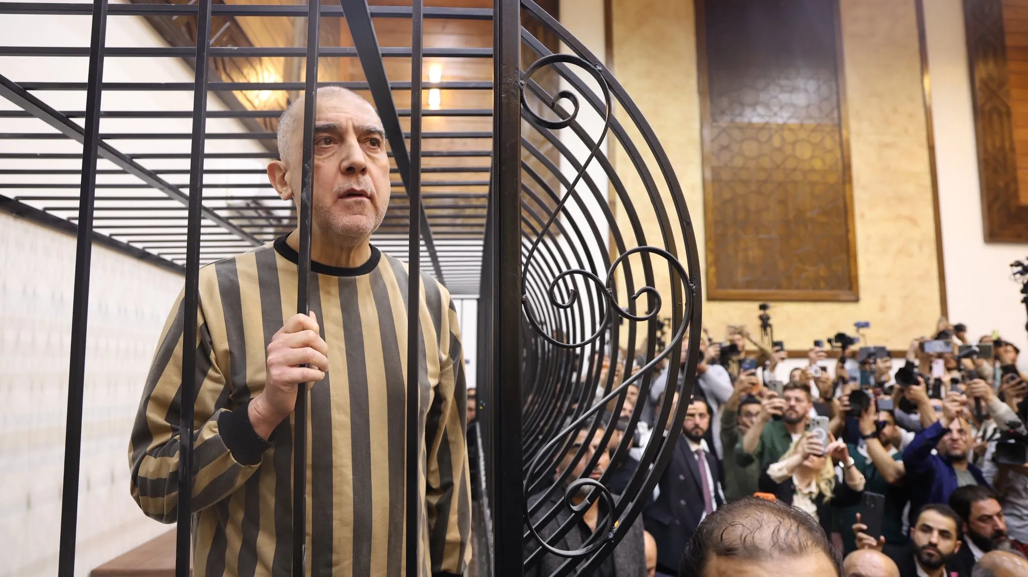 التايمز البريطانية: ابن خالة بشار الأسد داخل قفص الاتهام مرتدياً زي السجن